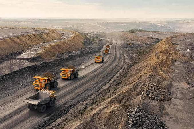 Open-pit mining site with heavy trucks transporting materials, reflecting Saudi Arabia’s industrial growth under Vision 2030.